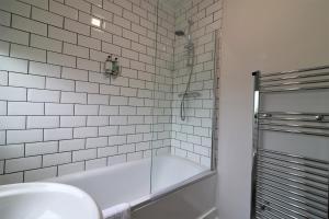 a white bathroom with a tub and a shower at Signature - Caldercruix House in Caldercruix