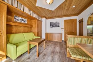 a living room with a green couch and a table at Landhaus Eichenhof in Saalbach Hinterglemm