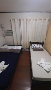um pequeno quarto com duas camas e uma cortina em Dion's Place em Iloilo