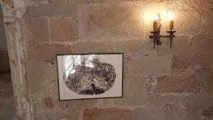 uma imagem pendurada numa parede de tijolos com duas velas em La Maison des Echevins em Vabres-lʼAbbaye