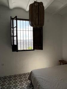 1 dormitorio con 1 cama y ventana en una habitación en Casa Juncares, en Iznájar