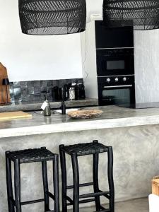 una cocina con dos taburetes negros en un mostrador en Casa Juncares, en Iznájar