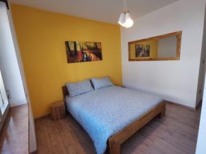 a bedroom with a bed in a yellow wall at Appartamento di design sull'Altopiano di Asiago in Tresché Conca