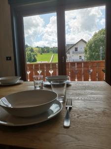 una mesa con un plato y un tenedor y una ventana en Appartamento di design sull'Altopiano di Asiago en Tresché Conca