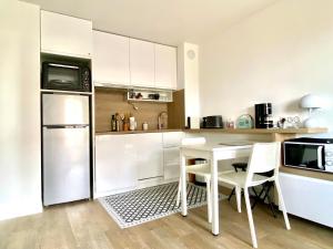 a white kitchen with a table and a refrigerator at LESPARISNORMANDS - le bon pressoir de Villers in Villers-sur-Mer