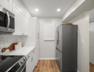 a kitchen with a stainless steel refrigerator and white cabinets at Beach Tennis 217 in Coquina Gables