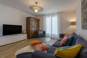 uma sala de estar com um sofá azul e uma televisão de ecrã plano em Maison Névez Campagne Calme Piscine em Clohars-Fouesnant