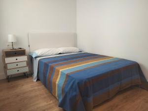 sypialnia z łóżkiem z paskowym kocem i stolikiem nocnym w obiekcie Cómodo apartamento en zona antigua dos w mieście Pontevedra