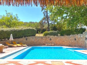 a swimming pool with chairs and a stone wall at Appart Karibu in Callian