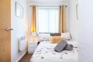 ein Schlafzimmer mit einem Bett mit Kissen und einem Fenster in der Unterkunft Executive 2 Bed Apartment with Free Parking by Amazing Spaces Relocations Ltd in Warrington
