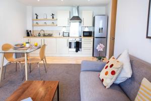 a kitchen and living room with a couch and a table at Executive 2 Bed Apartment with Free Parking by Amazing Spaces Relocations Ltd in Warrington