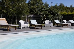 a group of lounge chairs and a swimming pool at Appartement Calme Campagne Piscine in Clohars-Fouesnant