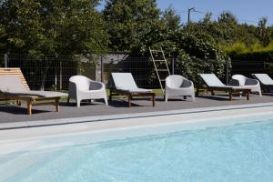 a group of lounge chairs and a swimming pool at Maison Coz Campagne Calme Piscine in Clohars-Fouesnant