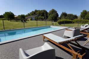 une piscine avec deux chaises longues et une piscine dans l'établissement Maison Coz Campagne Calme Piscine, à Clohars-Fouesnant