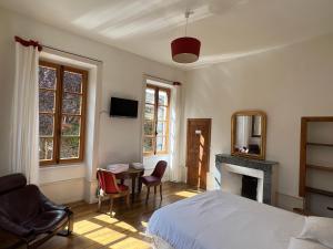 a bedroom with a bed and a table and a fireplace at Chambres d'Hôtes Les Tapies in Agen dʼAveyron