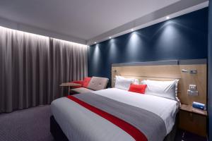 a hotel room with a large bed with red pillows at Holiday Inn Express Ramsgate – Minster by IHG in Minster