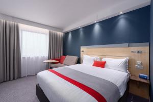 a hotel room with a large bed with red pillows at Holiday Inn Express Ramsgate – Minster by IHG in Minster