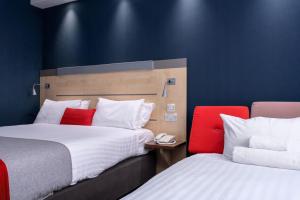 a hotel room with two beds and a red chair at Holiday Inn Express Ramsgate – Minster by IHG in Minster