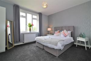 a bedroom with a large bed and two windows at Signature - Carfin House in Carfin