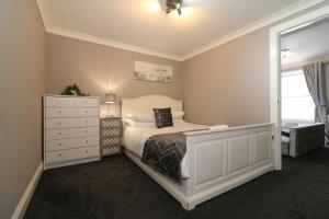a bedroom with a bed and a dresser and a mirror at Signature - Kirkhill Lower in Kirkmuirhill