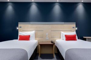 two beds with red pillows in a hotel room at Holiday Inn Express Ramsgate – Minster by IHG in Minster