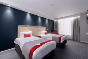 a hotel room with two beds with red accents at Holiday Inn Express Ramsgate – Minster by IHG in Minster