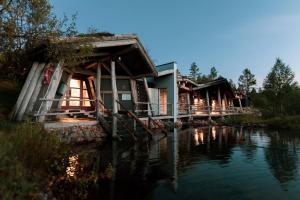 une rangée de cottages à côté d'une étendue d'eau dans l'établissement Fell Centre Kiilopää, Hotelli Niilanpää, à Saariselka