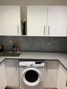 een keuken met een wasmachine onder de toonbank bij 3 Bedroom Flat in King’s Cross, St Pancras’s. 2 minutes to Euston. in Londen