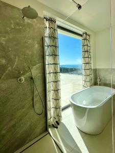 a bathroom with a tub and a shower with a window at Maximilian Suites in Trieste