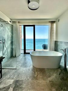 La salle de bains est pourvue d'une baignoire et offre une vue sur l'océan. dans l'établissement Maximilian Suites, à Trieste