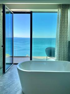 uma banheira na casa de banho com vista para o oceano em Maximilian Suites em Trieste