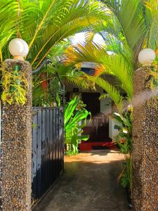 a black gate with palm trees in a driveway at Pranu House in Nilaveli