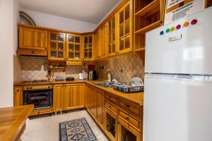 a kitchen with wooden cabinets and a white refrigerator at Hostel Nena Semi in Tirana