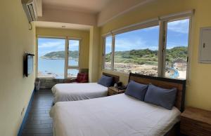 a hotel room with two beds and a view of the ocean at Matsu Island View Restaurant Bed and Breakfast in Nangan