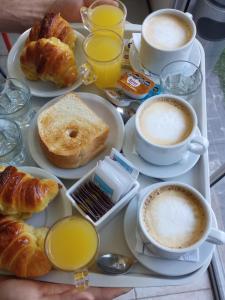 a tray of breakfast food with cups of coffee and croissants at Il Point Hostel Cafe in Neuquén