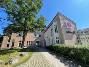 a building with a tree in front of it at 1, 2, sleep Boardinghouse Unterschleißheim Zentrum in Unterschleißheim
