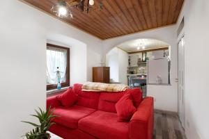 ein rotes Sofa im Wohnzimmer mit Küche in der Unterkunft Casa del sole in Toceno