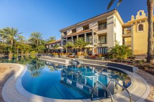 a swimming pool in front of a building at Unique Club at Lopesan Costa Meloneras Resort in Maspalomas