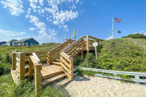 a wooden stairway on a beach with a cross on a hill at Pine Knoll Nest in Pine Knoll Shores
