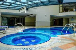a large swimming pool in a building with a large blue tub at The Smart Concierge - Time Place in Dubai