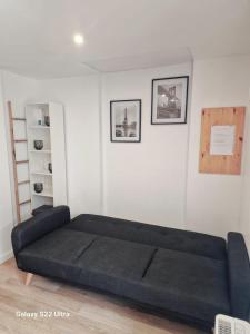 a black couch in a room with a white wall at Charment studio proche Paris 15 in Malakoff