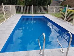 una piscina azul con 2 sillas. en KippaRing Village Motel (Near Redcliffe) en Redcliffe