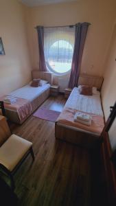 two beds in a room with a window and a chair at Hotel Mikorzyn in Ślesin