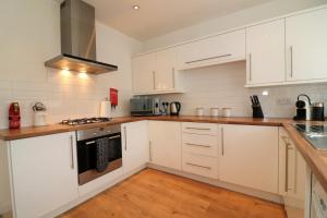 a white kitchen with wooden floors and white cabinets at Signature - Gordon House in Glasgow