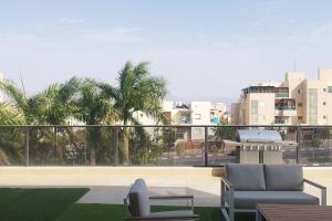 a balcony with a couch and a view of a city at YalaRent Seasons 4 bedroom apartment with jacuzzi in Eilat