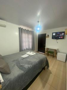 a bedroom with a bed and a flat screen tv at Suites da Rota - Pomerode SC in Pomerode