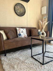 a living room with a brown couch and a table at Logement cosy indépendant avec jardin et Parking in Cornillé