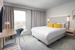 a hotel room with a bed and a large window at Courtyard by Marriott Paris Charles de Gaulle Central Airport in Roissy-en-France +30 photos