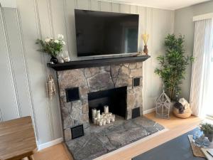 a living room with a stone fireplace with a flat screen tv at Thames River Cottage in Uncasville