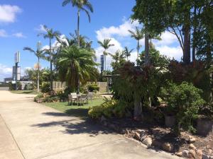einen Park mit Palmen und Stühlen und einen Gehweg in der Unterkunft KippaRing Village Motel (Near Redcliffe) in Redcliffe